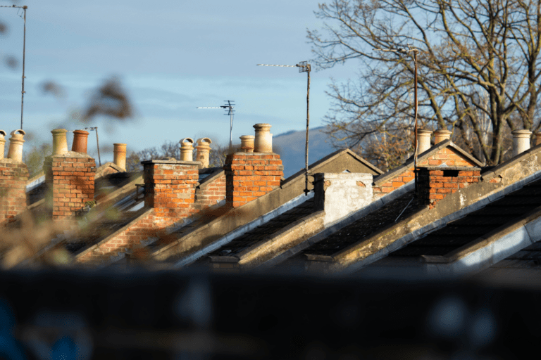 Rooftops of UK houses and blue sky.