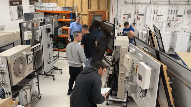 Overview of a training setting with trainees looking at various battery storage units.