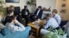 Minister for Energy Consumers Miattah Fanhbulleh is pictured with a group of people sitting on sofas inside a home.