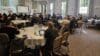 A group of people sitting in a room at round tables.
