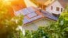 A domestic roof covered in solar panels with the sun shining on it.