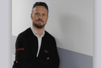 Man in branded jacket leaning on white wall