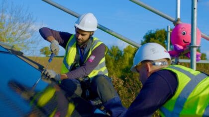Two installers pictured on a roof installing a solar panel