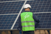 Solar panels and installer wearing high-viz jacket and white hard hat